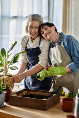 Two women in aprons planting a plant in a pot together.
