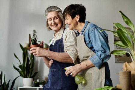 Two women in aprons care for a potted plant together.