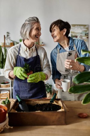 Téléchargez les photos : Two women in gardening aprons chatting. - en image libre de droit