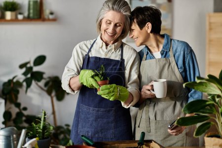 Téléchargez les photos : Un couple lesbien mature et aimant portant des tabliers, prenant soin des plantes. - en image libre de droit