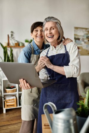 Téléchargez les photos : Deux femmes travaillent sur ordinateur portable dans une cuisine élégante. - en image libre de droit