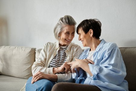 Two elderly women enjoy a heartwarming conversation on a couch.