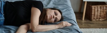 Photo for A middle-aged woman lies on a bed with crossed arms. - Royalty Free Image