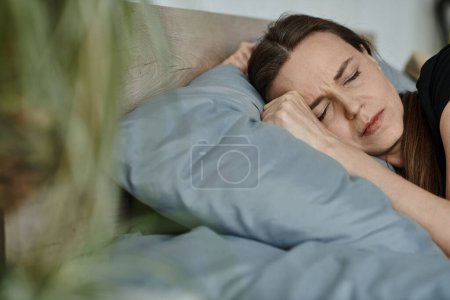 Middle-aged woman peacefully rests in bed, head on pillow.