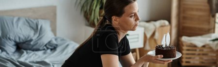 Photo for Woman seated with cake on bed - Royalty Free Image