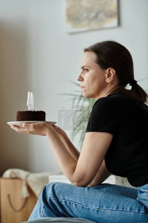 Woman sitting on couch, holding birthday cake.