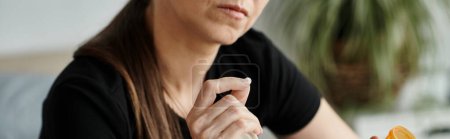 Foto de A woman sits with pills in hand, lost in thought. - Imagen libre de derechos
