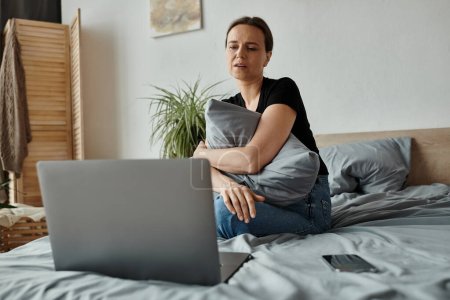 Middle-aged woman finds solace in therapy session on laptop.
