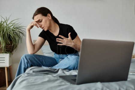 Woman sitting on bed with laptop.