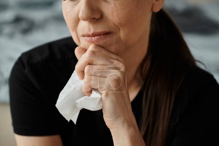 Middle-aged woman holding a tissue in her hand, showing emotional vulnerability.