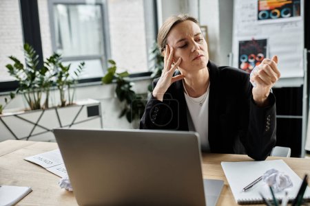 Woman in office experiencing stress and frustration, hand on head.