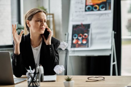Woman at desk in middle of call, overwhelmed by stress.