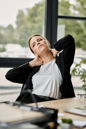 Middle-aged woman in distress sits on office chair.
