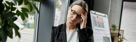 Photo for A middle-aged woman holding her head up, stress. - Royalty Free Image