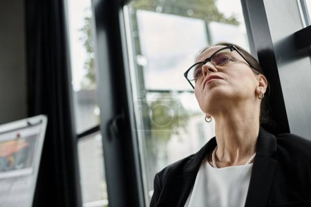 Middle-aged woman with glasses gazes away, depression, lost in thought.