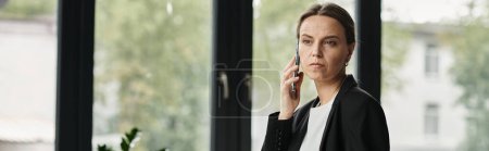 Photo for Woman in a moment of contemplation, conversing on phone by window. - Royalty Free Image