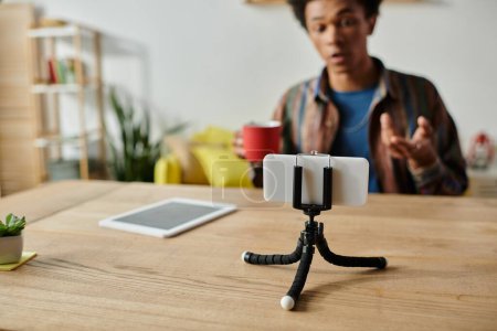 Young African American male blogger recording himself on phone on tripod.