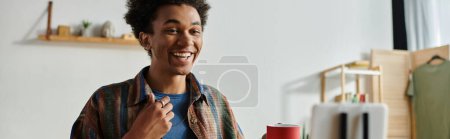 Foto de A young man smiles while holding a cup of coffee. - Imagen libre de derechos
