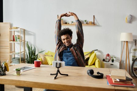 Young African American man stretches arms while chatting on phone.