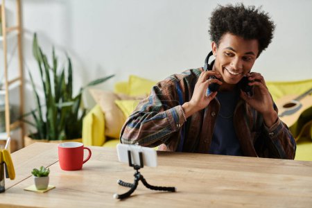 A young man with headphones and coffee, chatting on the phone.