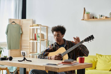 A young man, playing an acoustic guitar, creates music in his cozy living room.