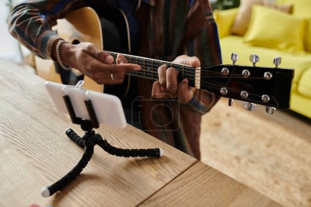 Téléchargez les photos : A man skillfully plays an acoustic guitar on a stand. - en image libre de droit