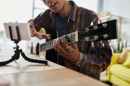 Foto de Young man passionately plays acoustic guitar at outdoor venue. - Imagen libre de derechos