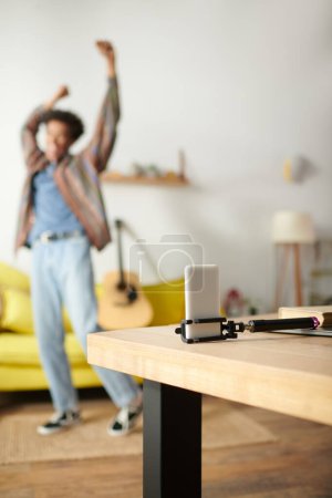 Young African American man dancing energetically on a yellow couch in a lively living room.