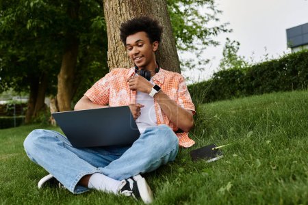 Téléchargez les photos : Young man, laptop, grass, relaxing in the park. - en image libre de droit