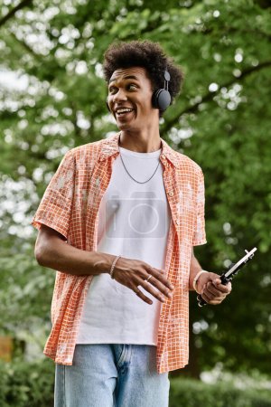 Foto de A young man with headphones walks in the park. - Imagen libre de derechos