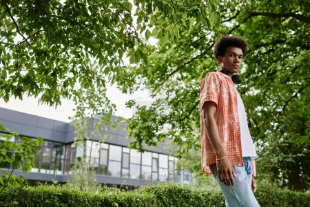 Téléchargez les photos : Young man of African American descent standing in park near building. - en image libre de droit