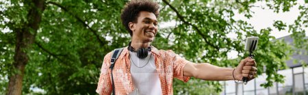 Téléchargez les photos : Young man, African American, holding a microphone in a park. - en image libre de droit