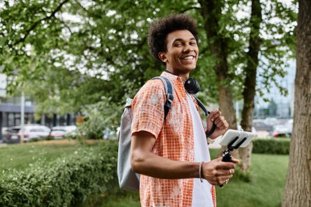 Foto de A young African American man capturing memories, walking in a park. - Imagen libre de derechos