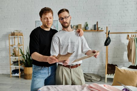 Zwei Männer, Designer, arbeiten in einem kreativen Atelier zusammen, um trendige Kleidung zu entwerfen.