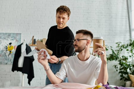 Foto de A man sits on a bed as his partner holds a piece of paper in a designer workshop. - Imagen libre de derechos