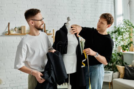 Zwei Männer, von denen einer Stoff hält, während der andere Skizzen entwirft, arbeiten in ihrer Werkstatt am Modedesign.