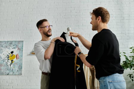 Deux hommes, un couple gay, debout ensemble dans un atelier de designer, collaborant sur des vêtements à la mode.