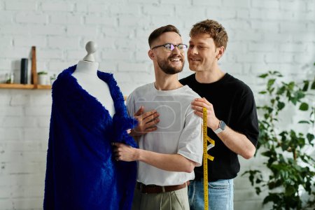 Zwei männliche Designer stehen neben einem Kleid auf einer Schaufensterpuppe in einer Kreativwerkstatt.