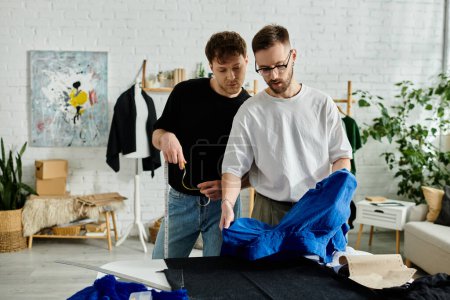 Foto de Dos hombres en taller de diseño, colaborando en atuendo de moda. - Imagen libre de derechos