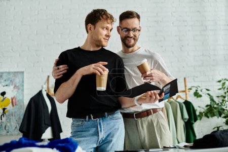 Foto de Two men, a gay couple, stand together in a designer workshop, passionately creating trendy attire. - Imagen libre de derechos