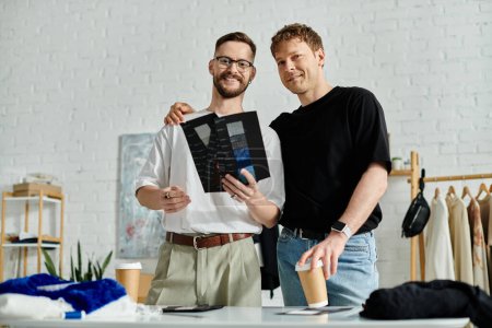 Téléchargez les photos : A gay couple, designers in love, stand triumphantly next to each other in their workshop. - en image libre de droit