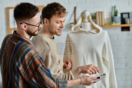 Two men, a gay couple in love, carefully examine a chic dress on a mannequin in their designer workshop.
