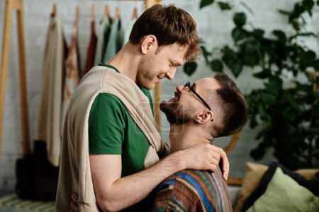 Foto de Dos hombres, una pareja gay, se ponen uno al lado del otro en un taller de diseño, colaborando en creaciones de atuendos de moda. - Imagen libre de derechos