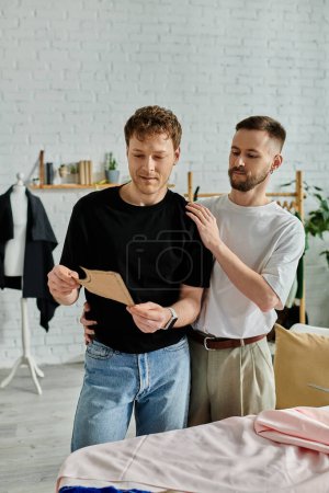 Two men, a gay couple, stand together in a designer workshop, collaborating on trendy attire.
