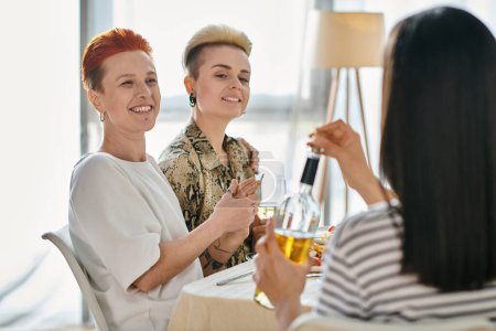 Téléchargez les photos : Deux femmes se détendre à une table, profiter du vin et de la conversation, avec des amis. - en image libre de droit