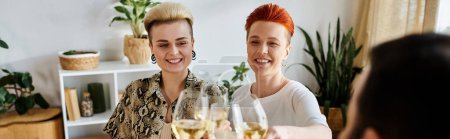 Foto de Dos mujeres diversas disfrutan del vino en una mesa con amigos. - Imagen libre de derechos