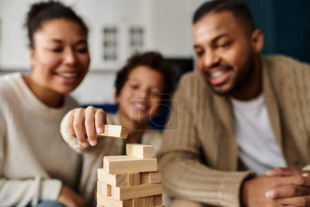 African american family builds wooden block tower with enthusiasm.