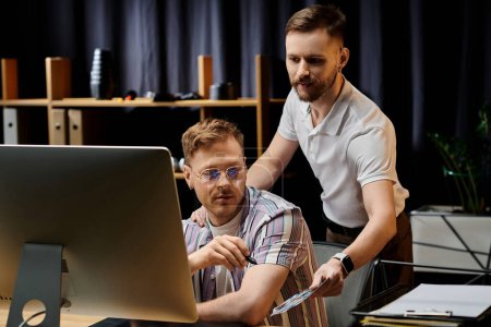 A gay couple in cozy attire working together, focused on a computer screen.