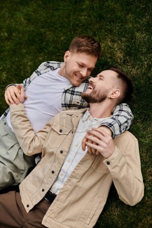 Photo for Happy gay couple in comfortable attire lounge on a lush green field. - Royalty Free Image