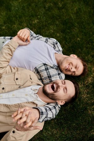 Photo for Two men in comfortable attire lying on lush green field. - Royalty Free Image